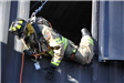 Firefighter descending from window of training facility via rope