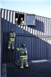 Firefighter descending from training facility window via rope