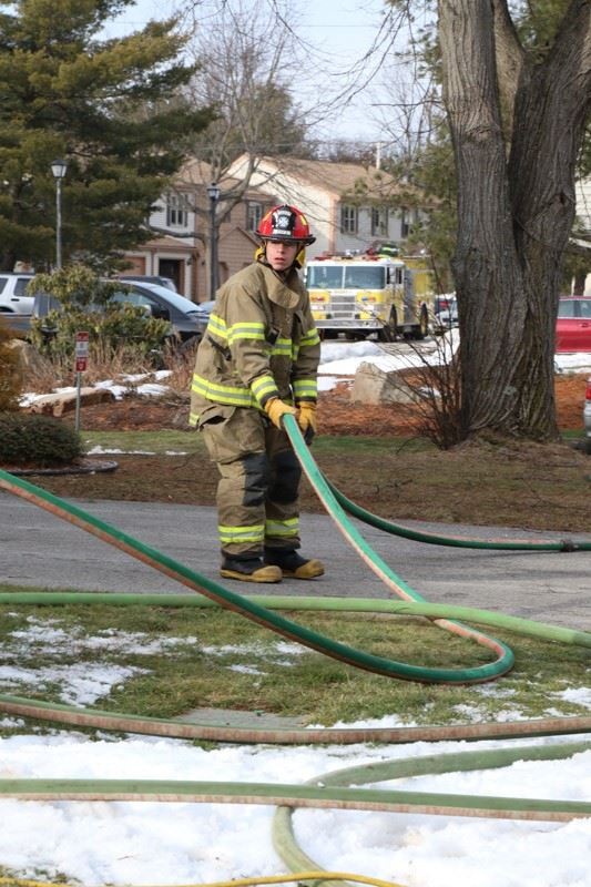Firefighter in gear running a hose