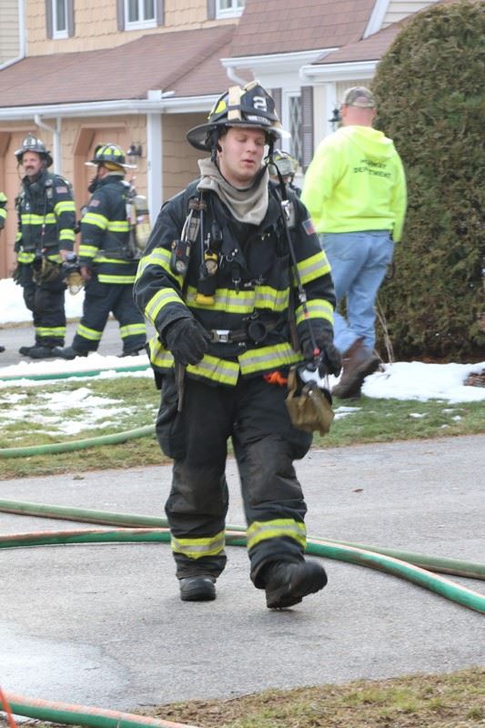 Firefighters in gear at the site of a house fire
