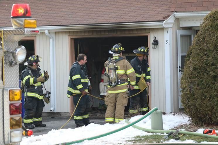 Firefighters in gear at the site of a house fire