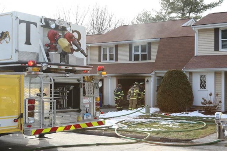 Firefighters and Fire Engine in front of a Smoking House