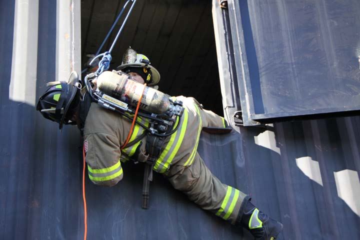 Firefighter descending from training facility window via rope