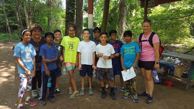 Youths and mentor gathered for picture in wooded area