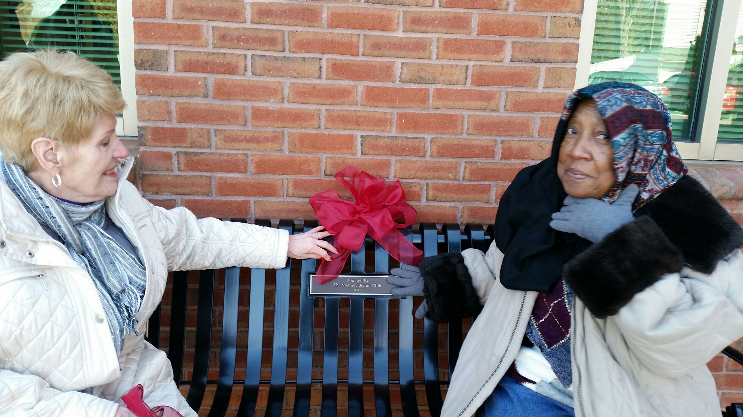 Two people posing with the new Stepney Bench